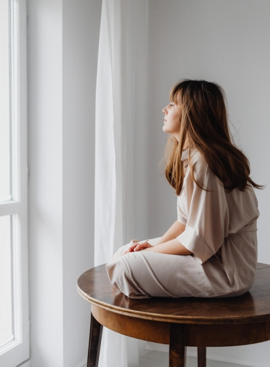 Person sitting by a window with soft light, symbolizing finding your way out of the darkness
