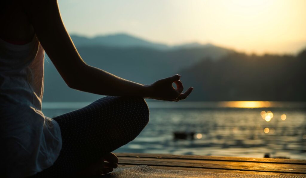 meditation tips for allowing and letting go with hand resting on knee at beach