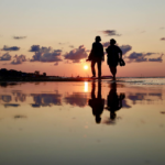 Two people walking together in a shallow lake at sunrise, symbolizing intentional communication, emotional connection, and speaking with compassion