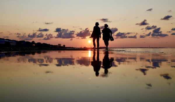 Two people walking together in a shallow lake at sunrise, symbolizing intentional communication, emotional connection, and speaking with compassion