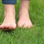 Bare feet gently walking through grass as a grounding practice for nervous system regulation, self compassion, and emotional clarity.