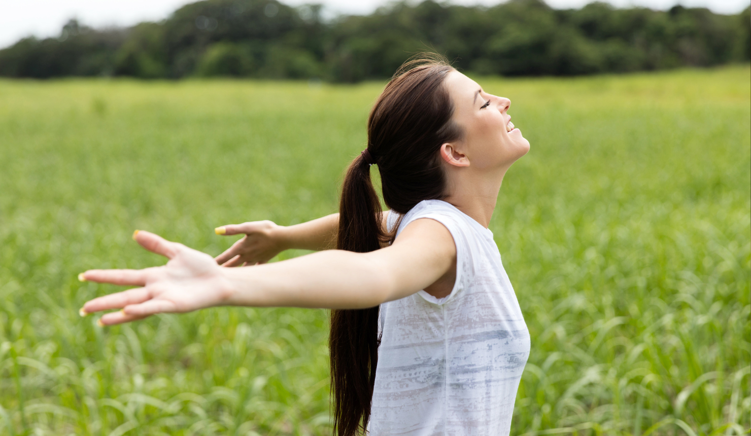 Woman standing in an open field with arms relaxed, representing internal freedom and peace