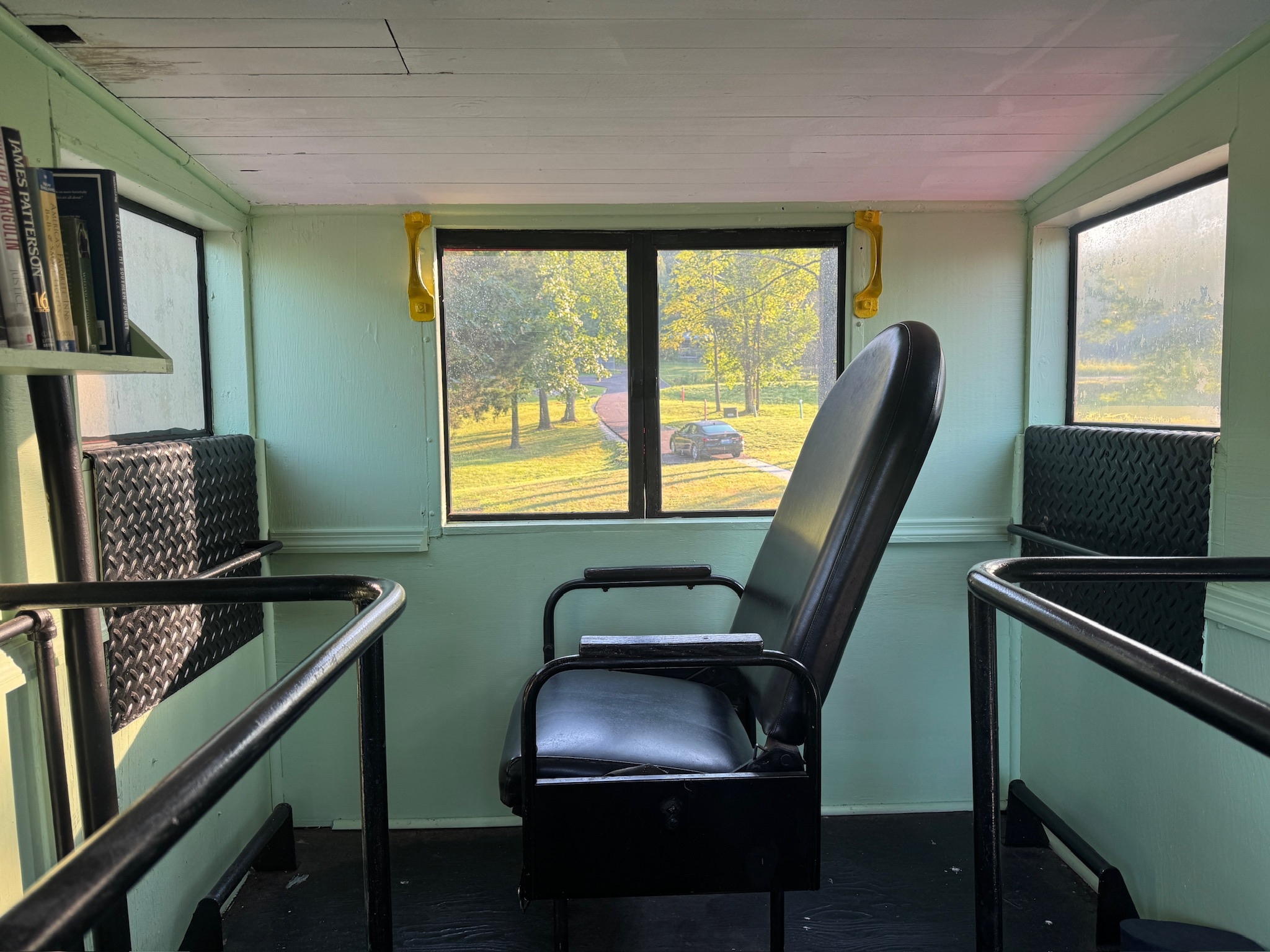 Woman writing in a renovated train car surrounded by books overlooking a lake