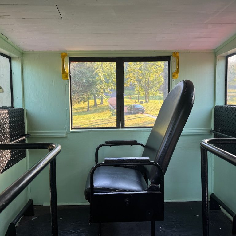 Woman writing in a renovated train car surrounded by books overlooking a lake